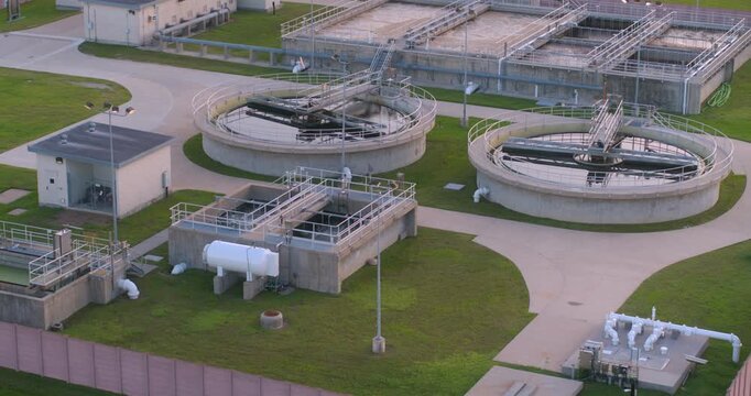 This birds eye drone view captures a wastewater treatment plant from directly overhead, showing the geometric layout of clarifiers, aeration basins, settling tanks, and other industrial infrastructure