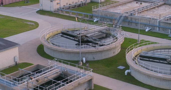 This birds eye drone view captures a wastewater treatment plant from directly overhead, showing the geometric layout of clarifiers, aeration basins, settling tanks, and other industrial infrastructure