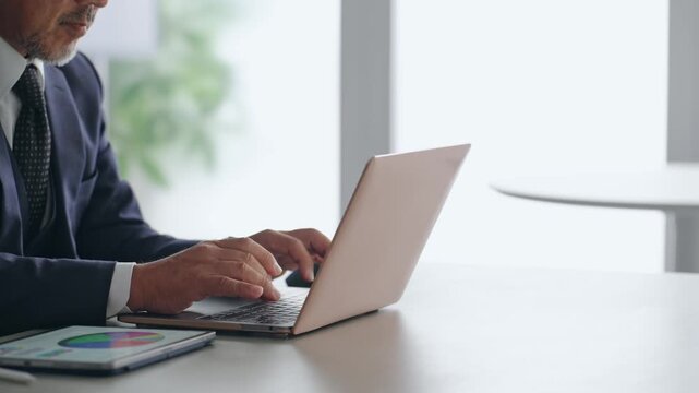 A male business person working on a laptop computer.