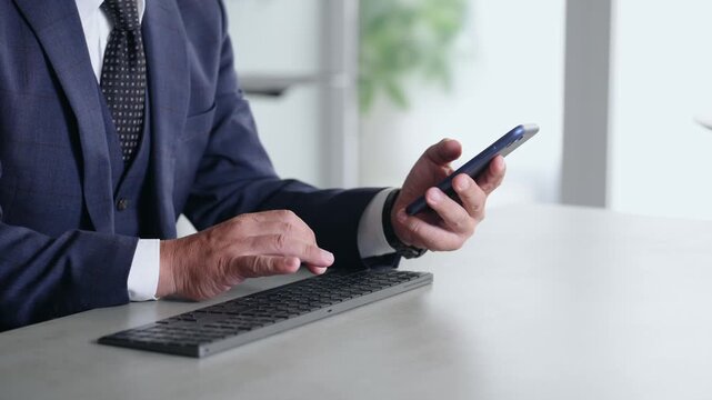 スマホとPCを使って作業する男性