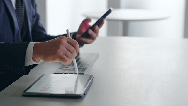 スマホとタブレットPCを使って作業する男性