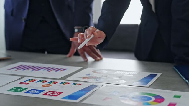 Male and female business professionals holding a meeting while looking at documents.
