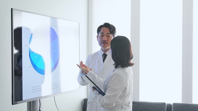 画面を見ながら会議する白衣の男女グループ