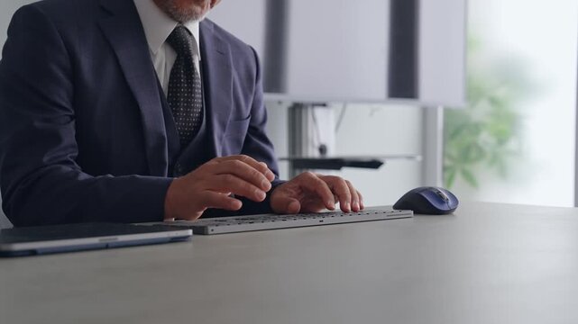 A male business person operating a PC keyboard.