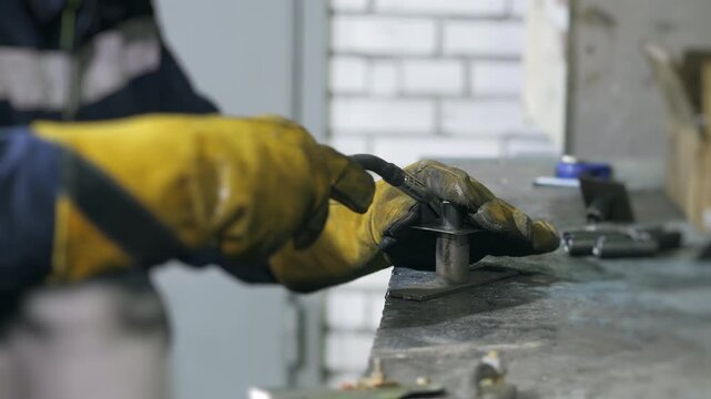 Skilled industrial worker aligns metal parts and performs arc welding in factory workshop. Metal fabrication, steel assembly and manufacturing process