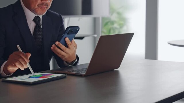 A man working using a smartphone and a tablet PC.