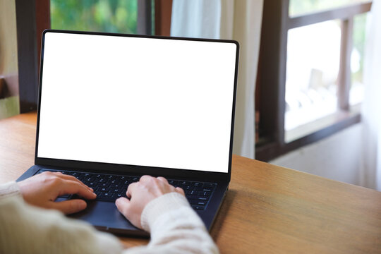 Mockup image of a woman working and typing on laptop computer with blank white desktop screen at home