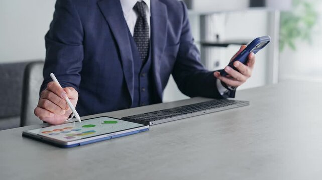 スマホとタブレットPCを使って作業する男性