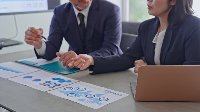A group of business people talking while looking at documents.
