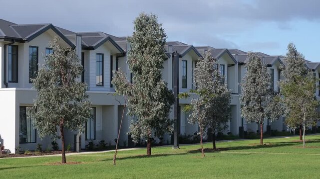 A row of newly developed two-story townhouses facing a green park in the outer western suburb of Truganina, Melbourne, Australia. Urban sprawl and real estate mass production.
