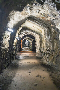 A glowing corridor within the Salt Mine of Bex in Switzerland reveals carved walls and rail tracks, showcasing the quiet geometry and depth of an active subterranean tunnel.