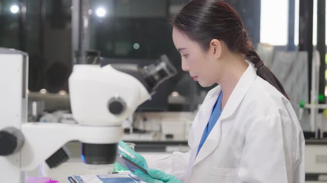 Young researchers are analyzing samples and taking notes in the science lab. A team of lab technicians is working with microscopes and recording research data.