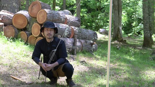森林でテントを張るペグを打つ楽しむ男性と自然体験のアウトドアイメージの動画