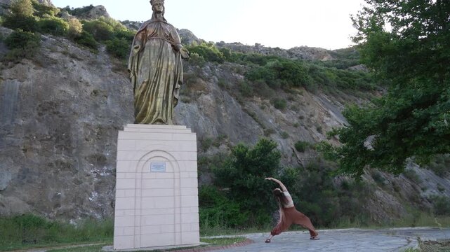 Woman practicing yoga near Virgin Mary statue