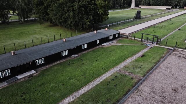 Drone passes preserved wooden barracks and guarded camp perimeter in Poland