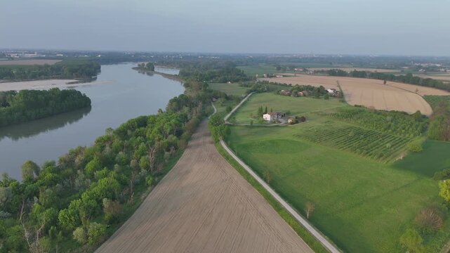 Po River wetlands and farmland along the Lombardy and Emilia Romagna border in northern Italy, revealing river meanders, agricultural fields, and rural landscape, drone pullback shot.
