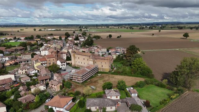 Drone establishing shot above Calendasco Castle near Piacenza, Emilia Romagna, Italy, revealing medieval fortress architecture, rural village fabric, and cultivated Po Valley farmland.