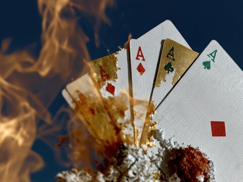 Four ace playing cards burning in orange fire flames for casino advertising, poker tournament promotion and gambling game design featuring textured surface and embers