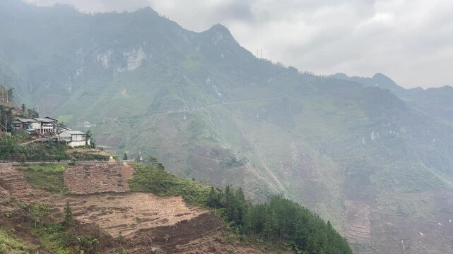 High angle view of cliffside houses terraced mountain slopes and turquoise Nho Que River flowing through Tu San Canyon in Ha Giang Vietnam