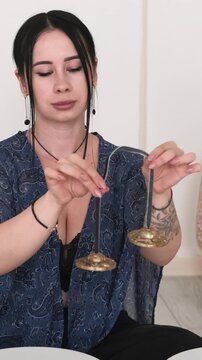 Vertical video. Tingsha bells. Sound meditation. Woman enjoying therapy wellness retreat healing treatment recreation process.