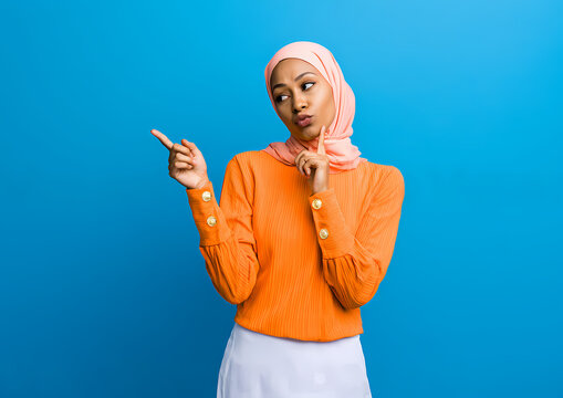 Portrait de Studio d'une Femme en Hijab Surprise Tenant un Smartphone - Expression de Choc, Pointant du Doigt et Concept de Promotion