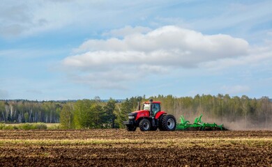 Fototapeta premium A tractor working in a field in spring. Agriculture, farming.