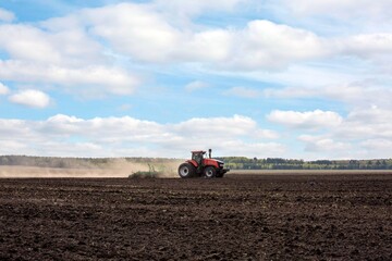 Fototapeta premium A tractor plowing a field in spring. Agricultural work, farming.