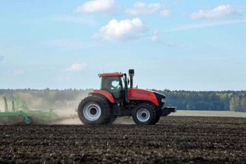 Obraz premium A tractor working in a field in spring. Agriculture, farming.