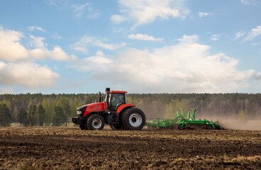 Obraz premium A tractor working in a field in spring. Agriculture, farming.