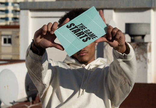 Mockup of young Man Holding a Blank Notebook cover on Rooftop