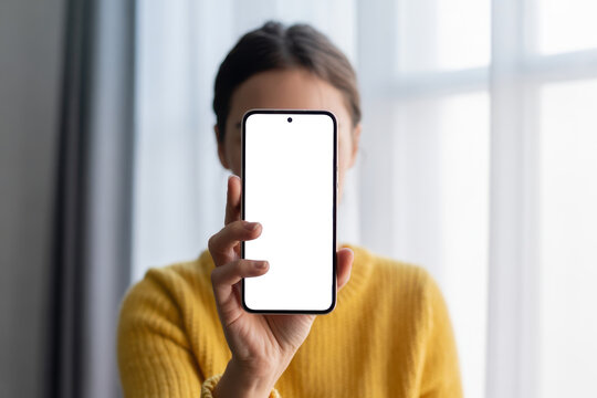 Woman holding a smartphone with a blank screen in front of her face