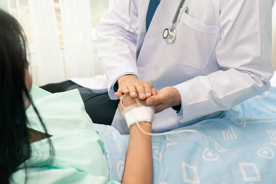 cheerful Asian doctor talking with young woman patient for monitoring and check up after surgery. doctor giving advice in the touchscreen to women to take care the lesion after out of hospital.