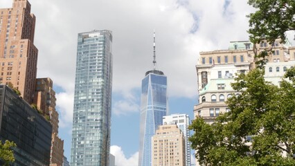 Naklejka premium New York City Manhattan Downtown Financial District, United States of America. World Trade Center skyscraper, tower building in FiDi. Modern business center from Battery park. Summer tree greenery