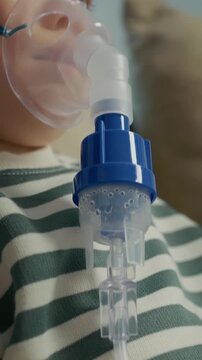 Vertical Screen: A child is using a nebulizer with a mask to receive steam inhalation for treating cough and respiratory issues at home. The device releases saline solution.