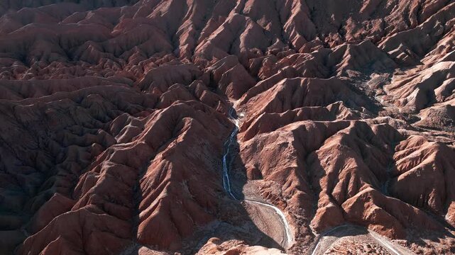 Bird's eye view over deeply eroded salt rock badlands with winding dry riverbed cutting through dramatic sharp ridges and ravines. Valle de la Muerte, Chile