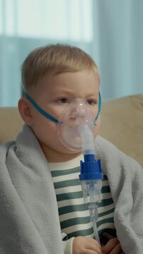 Vertical Screen: A child sits on a couch wearing a mask and uses a nebulizer to inhale saline solution for cough and respiratory issues. The child is focused on the treatment.