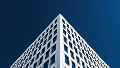 Fototapeta premium Stark white angular building corner meets deep blue sky