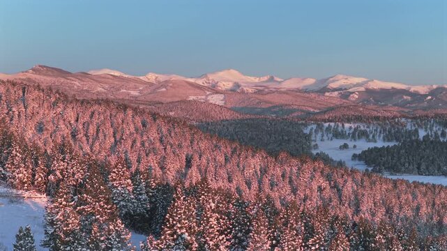 Alpenglow vibrant morning sunrise majestic purple Front Range Rocky Mountains Mount Blue Sky Evergreen Colorado aerial drone springtime snow Mt Evans wilderness landscape landmark backwards upwards