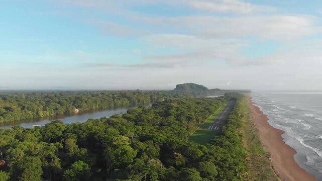 In Tortuguero National Park in Costa Rica, an aerial view captures an empty runway covered with lush rainforest, winding rivers and coastal shoreline within the protected Caribbean ecosystem.