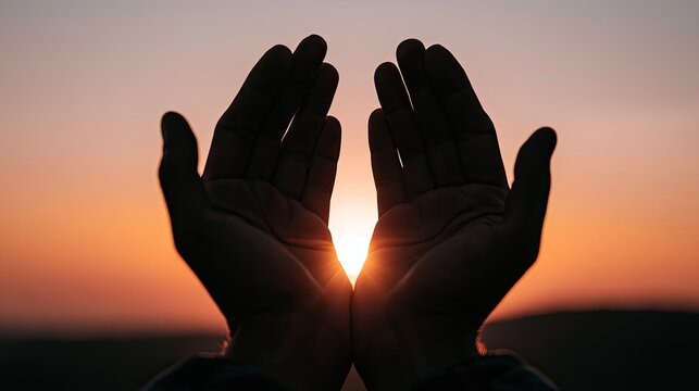 Cupped hands frame a bright sunset, evoking hope, peace, and a sense of receiving