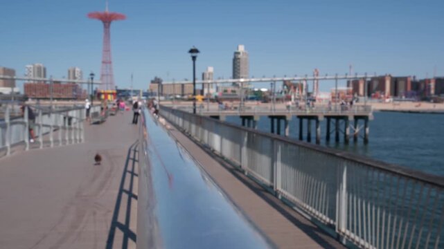 Coney Island beach, wooden pier promenade in Brooklyn, New York, United States. Boardwalk near retro luna park. Amusement park on ocean coast beach. People on waterfront summer holiday in NYC, USA