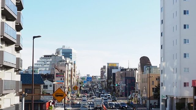 昼間の環七通りを走る自動車と東京の日常的な街並み
