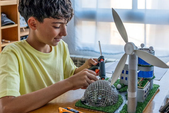 Teenager using a glue gun to make a project with recycled materials