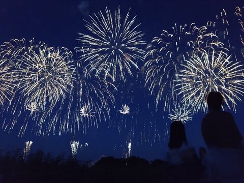Silhouettes of people watching a beautiful fireworks display in the summer night sky