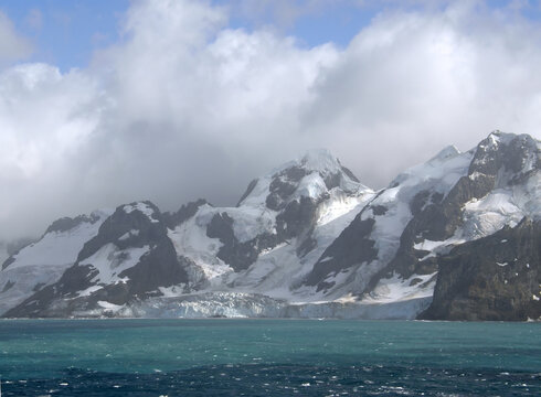  approaching the formidable mountain peaks, glaciers, and turquoise-colored water of elephant island,  on the antarctic peninsula, on a  summer cruise on a  sunny day     