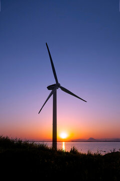 夜明け空に佇む風力発電機と再生可能エネルギー