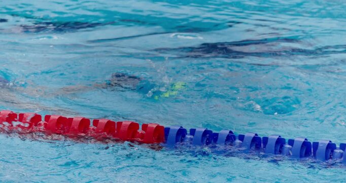 Kid swimmer with fins on the legs swimming in outdoor olympic swimming pool