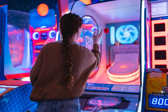 Young woman having fun playing a game in a modern, colorful arcade