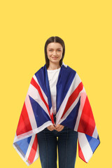 Obraz premium Young woman displays British flag. Pride and travel concept in bright environment