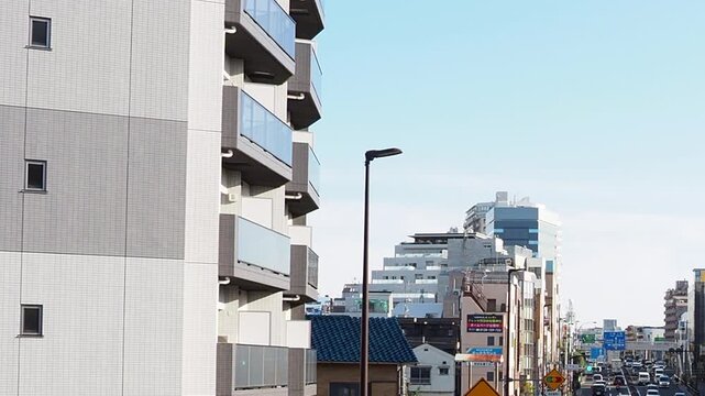 昼間の環七通りを走る自動車と東京の日常的な街並み